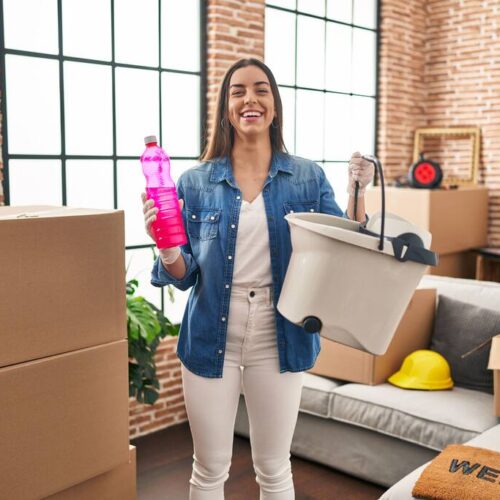 Hispanic woman moving to a new home cleaning the floor smiling and laughing hard out loud because funny crazy joke.